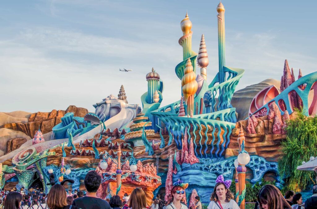 Un groupe de personnes debout devant un château coloré à Disneyland.