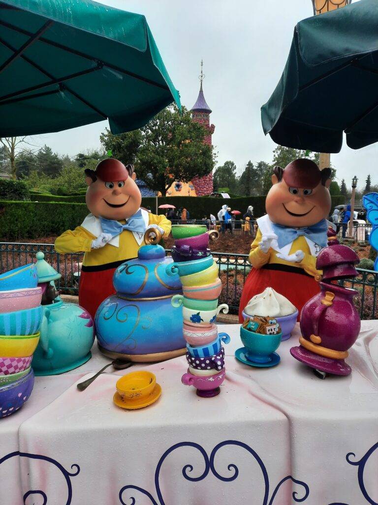 Une soirée thé fantaisiste avec des tasses à thé surdimensionnées et des statues de personnages animés au Curious Labyrinth d'Alice à Disneyland Paris.