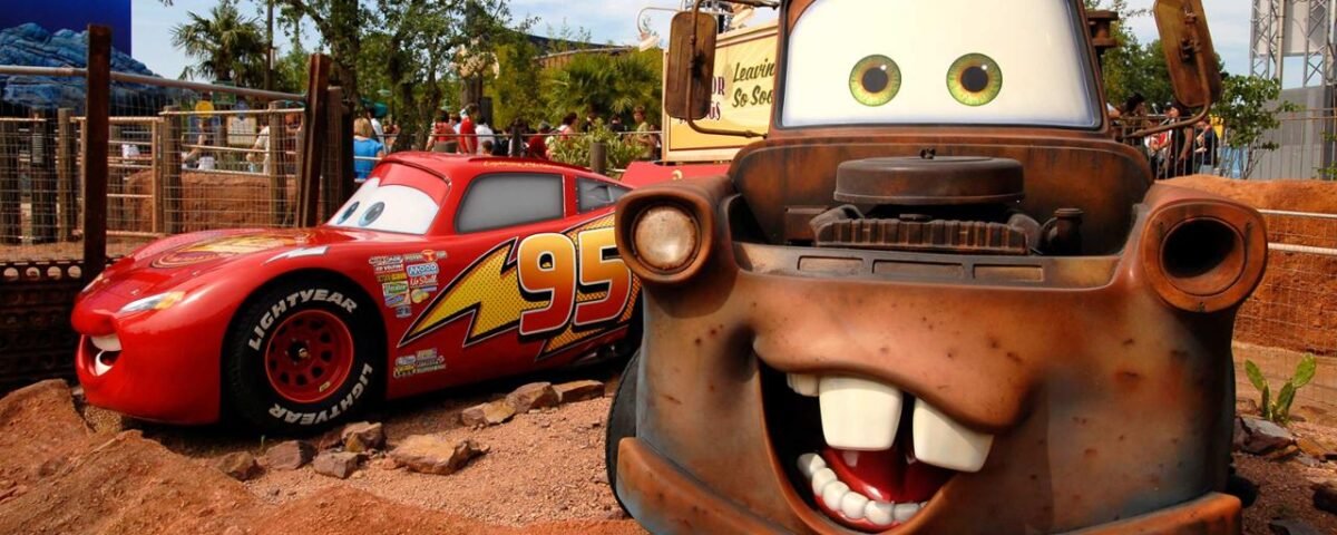 Des modèles grandeur nature de Lightning McQueen et Mater du film Disney's Cars exposés dans un parc à thème à Disneyland Paris, avec des détails vibrants et des arrière-plans colorés.