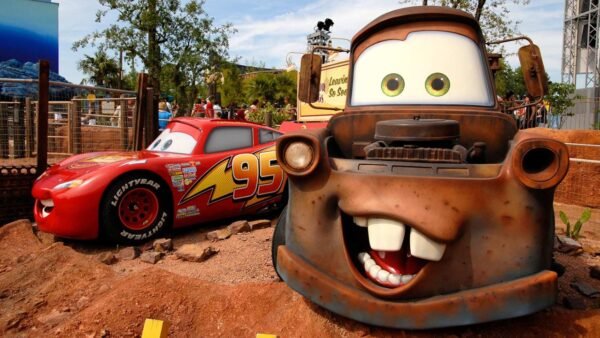 Des modèles grandeur nature de Lightning McQueen et Mater du film Disney's Cars exposés dans un parc à thème à Disneyland Paris, avec des détails vibrants et des arrière-plans colorés.