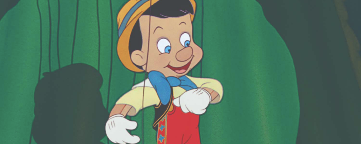 Une marionnette en bois animée ressemblant à Pinocchio de Disney, avec un chapeau jaune, un nœud papillon bleu, un short rouge et des gants blancs, est suspendue à des ficelles sur un fond vert.