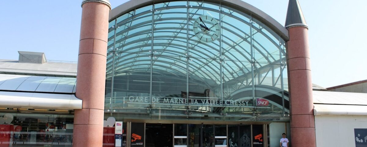L'entrée vitrée de la gare de Marne-la-Vallée – Chessy, dotée d'une horloge au-dessus de la porte et de deux tours cylindriques flanquant la structure, fait écho au Val d'Europe voisin avec son design moderne mais charmant.
