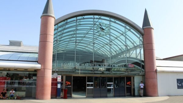 L'entrée vitrée de la gare de Marne-la-Vallée – Chessy, dotée d'une horloge au-dessus de la porte et de deux tours cylindriques flanquant la structure, fait écho au Val d'Europe voisin avec son design moderne mais charmant.