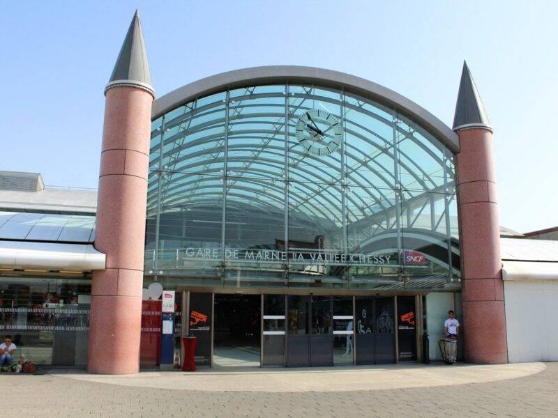 L'entrée vitrée de la gare de Marne-la-Vallée – Chessy, dotée d'une horloge au-dessus de la porte et de deux tours cylindriques flanquant la structure, fait écho au Val d'Europe voisin avec son design moderne mais charmant.