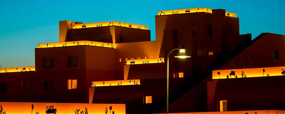 Un bâtiment avec des silhouettes de personnes illuminées sur le toit contre un ciel crépusculaire de Cheyenne, avec un lampadaire allumé au premier plan.