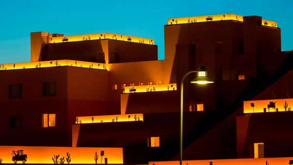 Un bâtiment avec des silhouettes de personnes illuminées sur le toit contre un ciel crépusculaire de Cheyenne, avec un lampadaire allumé au premier plan.