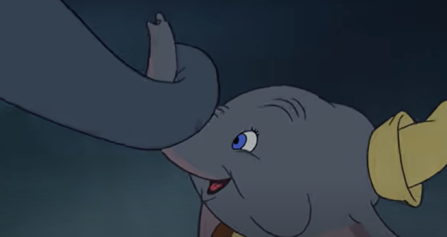 Un jeune éléphant de dessin animé aux grandes oreilles, coiffé d'un chapeau jaune, tient délicatement la trompe d'un autre éléphant avec son propre « mon tout petit », sur fond sombre.