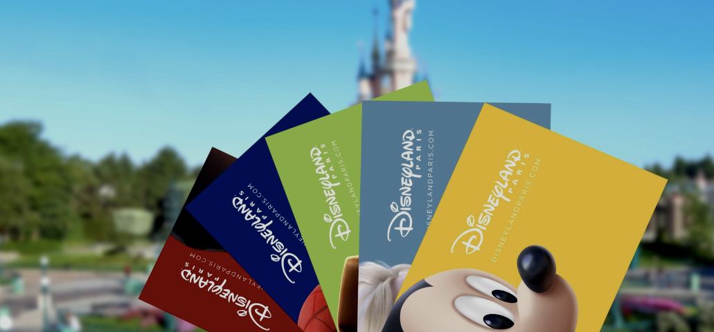 Quatre billets de Disneyland Paris présentent des motifs colorés, dont un représentant Mickey Mouse en gros plan. Un château flou sert de toile de fond enchanteresse.