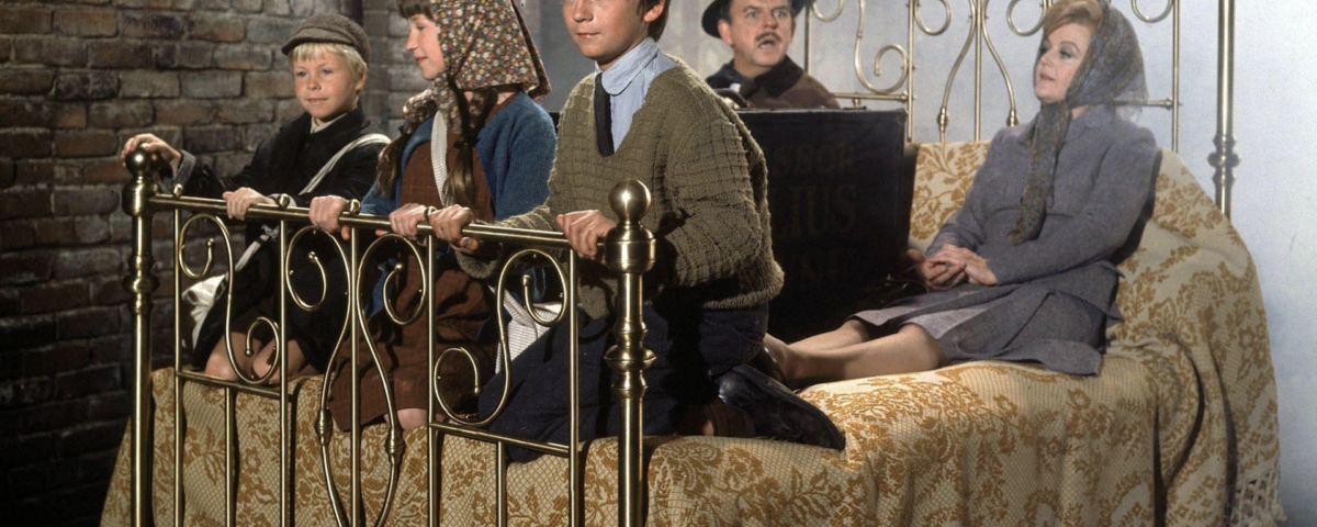 Cinq personnages sont assis sur un lit dans un décor fantaisiste, entouré de murs de briques et de vapeur. Vêtus de vêtements d'époque, ils semblent se livrer à une pratique enchanteresse de locomotion substitutive qui donne vie à toute la scène avec une touche magique.