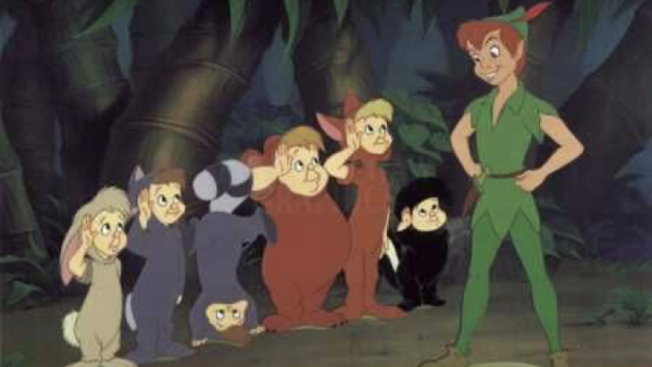 Un groupe d'enfants déguisés en animaux se tient dans une forêt, alignés à la manière indienne, avec un garçon en vêtements verts souriant avec confiance devant eux.