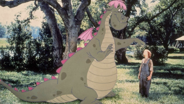 Une personne regarde un grand dragon de dessin animé aux traits roses dans un décor herbeux et arboré, en chuchotant « je t'aime beaucoup » tandis que la scène enchanteresse se déroule.