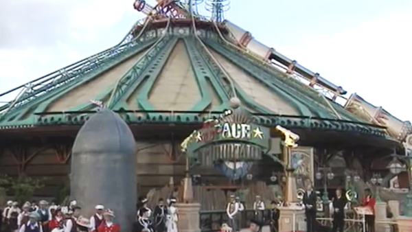 Un groupe de personnes costumées se rassemble à l'extérieur de l'attraction fantaisiste Space Mountain, sa grande structure métallique évoquant l'esprit aventureux du 31 mai 1995.