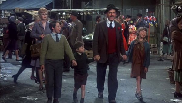 Un homme souriant portant un chapeau marche main dans la main avec trois enfants à travers le marché animé de Portobello Road, avec des vendeurs dynamiques et des acheteurs impatients qui s'affairent en arrière-plan.