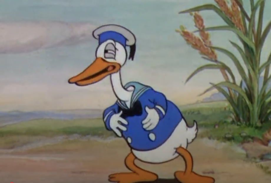 Un canard de dessin animé ressemblant à Donald Duck dans une tenue de marin bleu se tient à l'extérieur, tenant son ventre et plissant les yeux, avec des plantes et le ciel en arrière-plan.