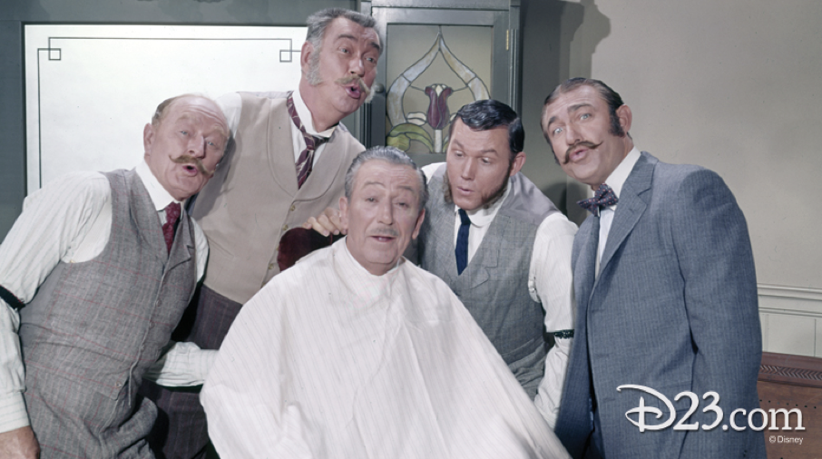 Cinq hommes, vêtus de costumes du début du XXe siècle, chantent ensemble dans un décor de salon de coiffure ; l'un d'eux est assis sur une chaise de barbier tandis que les autres, dont l'un porte un masque de style Zorro, se tiennent autour de lui.