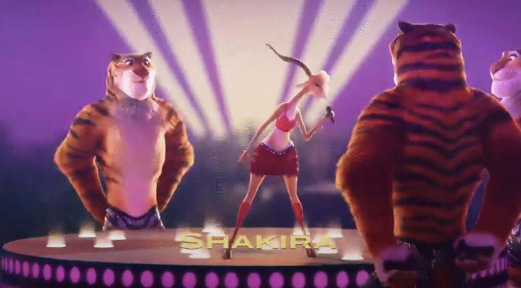 Une gazelle animée chante « Try Everything » sur scène, accompagnée de deux tigres dansant à ses côtés. Le nom « SHAKIRA » apparaît en jaune en bas.