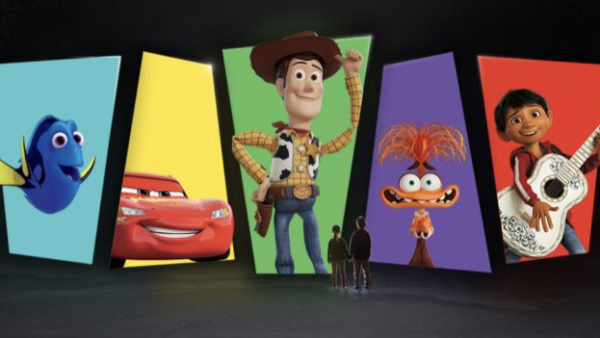 Cinq personnes se tiennent face à de grands écrans affichant les personnages bien-aimés de Pixar : Dory, Flash McQueen, Woody, une créature ressemblant à Muppet et un garçon avec une guitare.