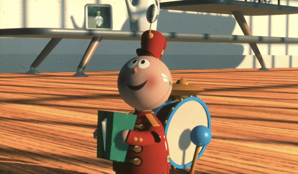 Une figurine de fanfare inspirée de Pixar avec un tambour, des cymbales et un grand chapeau se tient sur un plancher en bois dans une pièce bien éclairée.