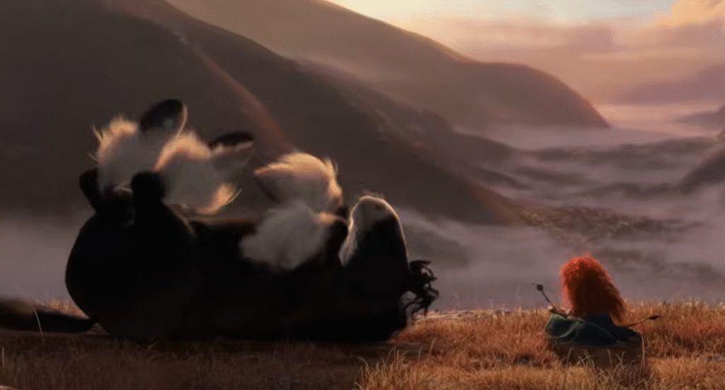 Une fille rebelle aux cheveux roux bouclés est assise sur une colline herbeuse au coucher du soleil tandis qu'un cheval noir est allongé sur le dos, les jambes tendues vers le ciel ; des montagnes brumeuses apparaissent en arrière-plan.