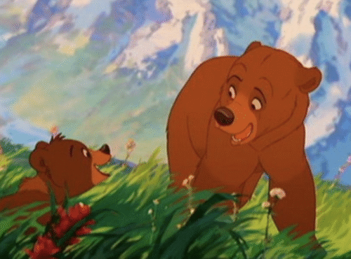 Deux ours bruns animés interagissent dans un champ d'herbe avec des fleurs colorées, avec pour toile de fond des sommets montagneux et un ciel bleu, rappelant Mon Frère Ours de la galaxie Disney.