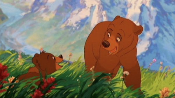 Deux ours bruns animés interagissent dans un champ d'herbe avec des fleurs colorées, avec pour toile de fond des sommets montagneux et un ciel bleu, rappelant Mon Frère Ours de la galaxie Disney.