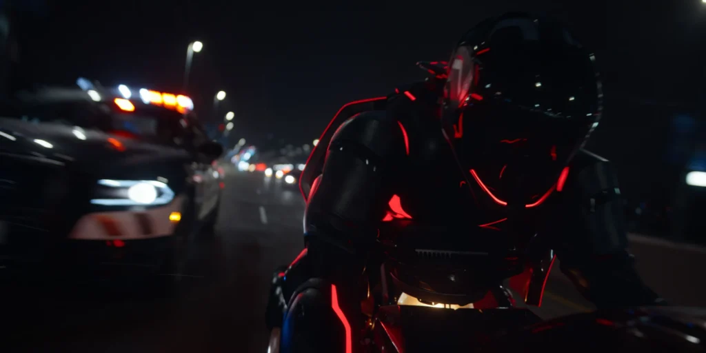 Une personne vêtue d'une combinaison noire futuriste avec des lumières rouges conduit une moto la nuit, poursuivie par une voiture de police dans une rue de la ville - évoquant les scènes de poursuite high-tech vues dans Tron : Ares de Disney avant sa date de sortie.