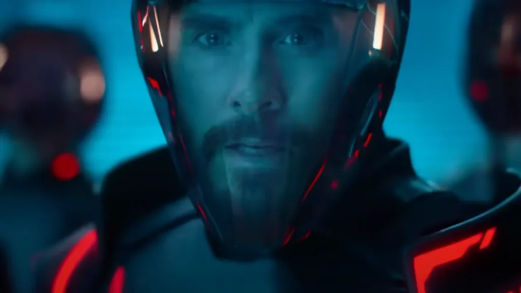 Personne portant un casque et une combinaison futuristes avec des accents rougeoyants, faisant face à l'avant dans un environnement éclairé en bleu, rappelant Tron : Ares de Disney.