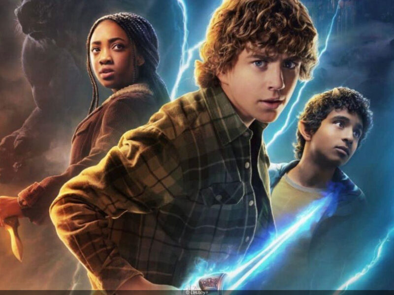 Trois jeunes gens se tiennent ensemble, chacun tenant une arme, tandis que des éclairs bleus et orange crépitent derrière eux dans cette scène saisissante de la bande-annonce de Percy Jackson Saison 2 sur Disney+.