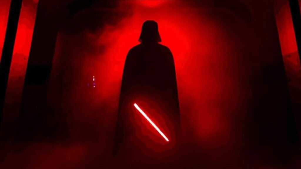 Un personnage sombre et capé se tient dans la lumière rouge et la brume, tenant un sabre laser lumineux Dark Vador pointé vers le bas - une icône incomparable de Star Wars.
