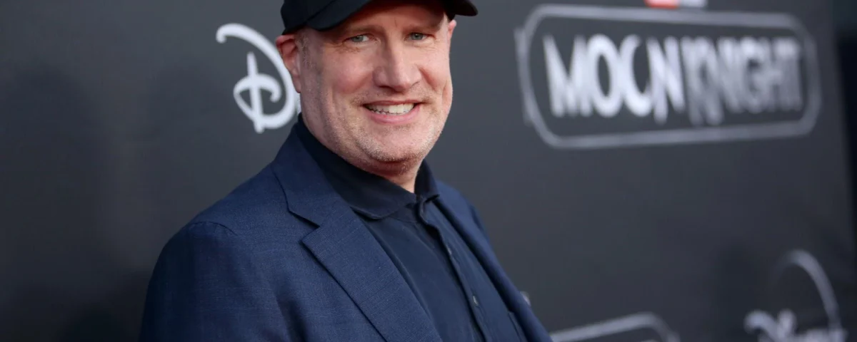 Un homme vêtu d'un blazer sombre et d'une casquette noire se tient devant une toile de fond de l'événement "Moon Knight" sur laquelle figurent les logos de Disney+ et de Marvel Studios.