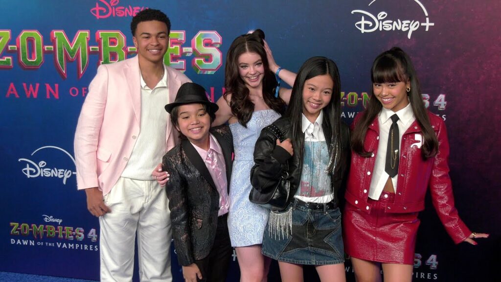 Cinq jeunes acteurs posent ensemble sur le tapis rouge lors de la première de Disney+ "Zombies 4 : Dawn of the Vampires", célébrant la dernière Série Musicale Live-action dans le plus pur style Disney Channel.