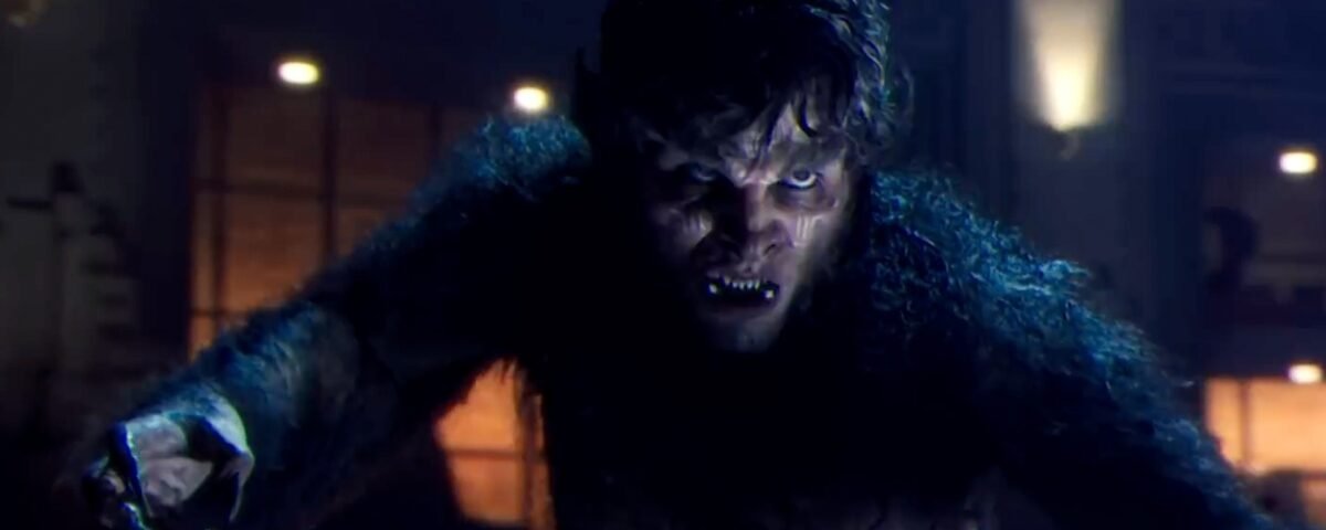 Une personne aux traits de loup-garou, rappelant le loup-garou de nuit du MCU de Marvel, est accroupie avec une expression intense dans une pièce faiblement éclairée.