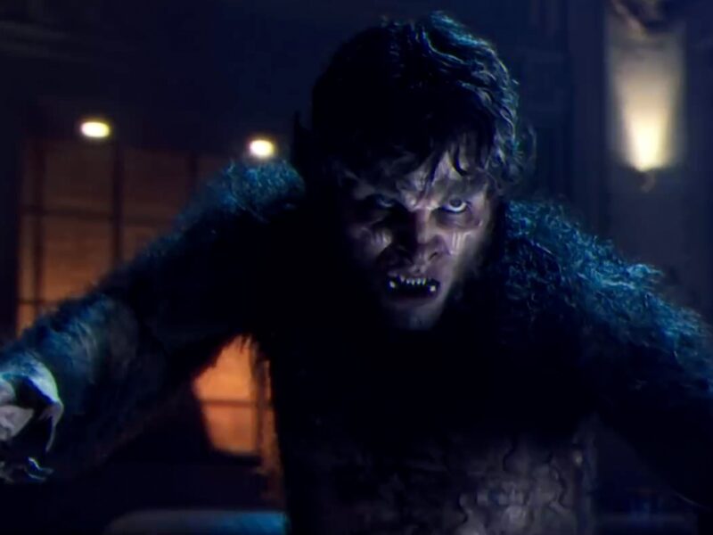 Une personne aux traits de loup-garou, rappelant le loup-garou de nuit du MCU de Marvel, est accroupie avec une expression intense dans une pièce faiblement éclairée.