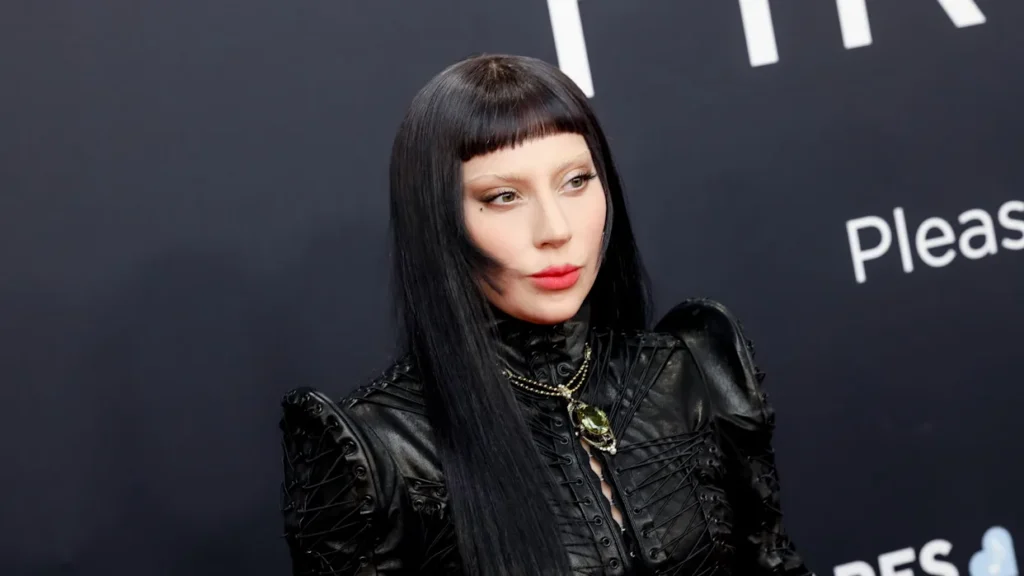 Une personne portant une tenue en cuir noir, de longs cheveux noirs et une frange émoussée, prenant la pose devant un arrière-plan sombre. Le Diable s'habille en Prada a été l'un des principaux symboles de l'événement.