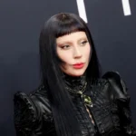 Une personne portant une tenue en cuir noir, de longs cheveux noirs et une frange émoussée, prenant la pose devant un arrière-plan sombre. Le Diable s'habille en Prada a été l'un des principaux symboles de l'événement.