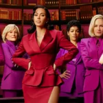 Six femmes se tiennent avec assurance devant des étagères, l'une d'entre elles en tailleur rouge au centre et les autres en tailleur violet assorti à ses côtés. Il s'agit d'une scène de responsabilisation tirée de la prochaine série Disney+ de Kim Kardashian, All's Fair.