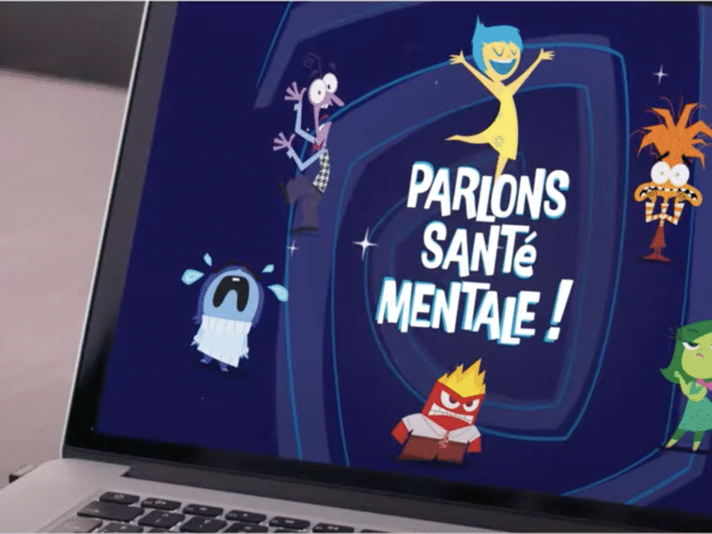 Un écran d'ordinateur portable affiche des personnages de dessins animés avec le texte français "Parlons santé mentale !" et la marque Disney/Pixar, vus par un enfant. La scène suggère que Disney France promeut Vice-versa pour susciter des conversations sur la santé mentale.