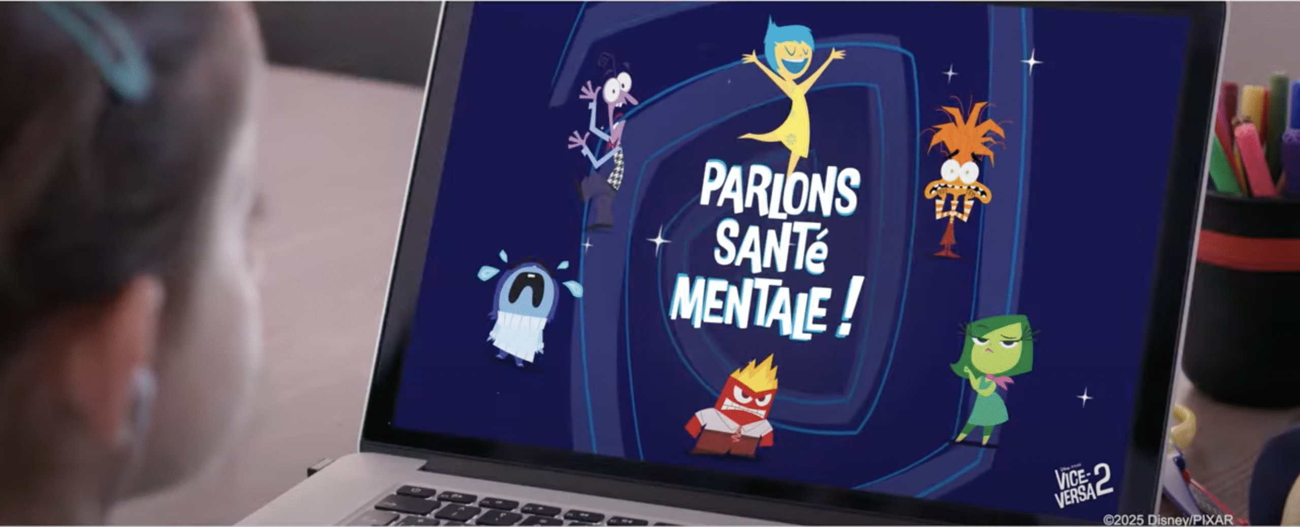 Un écran d'ordinateur portable affiche des personnages de dessins animés avec le texte français "Parlons santé mentale !" et la marque Disney/Pixar, vus par un enfant. La scène suggère que Disney France promeut Vice-versa pour susciter des conversations sur la santé mentale.