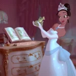 Une femme animée ressemblant à Tiana de Disney, vêtue d'une robe blanche et d'un diadème, tient une grenouille, debout à côté d'un bureau orné d'un livre ouvert - parfait pour une liste de naissance magique, dans une pièce élégante faiblement éclairée.