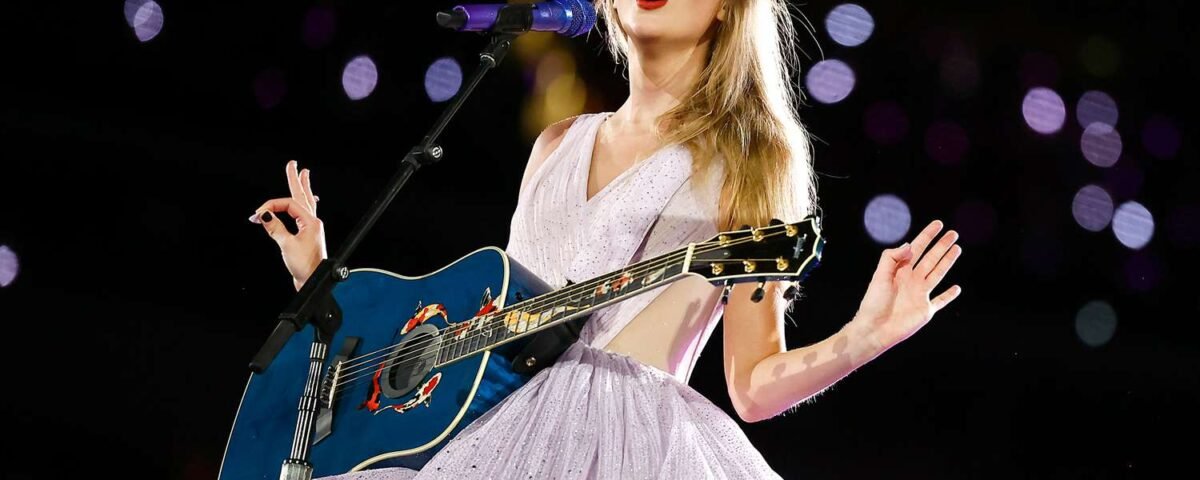Une femme vêtue d'une robe lavande chante sur scène, jouant d'une guitare acoustique bleue sous les lumières de la scène, capturant ainsi une ambiance magique de ciné-concert, parfaite pour tout fan de Disney+ ou de Taylor Swift.
