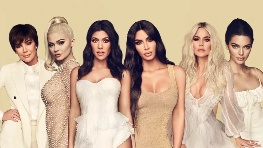 Six femmes vêtues de tenues neutres et blanches coordonnées se tiennent en rang sur un fond beige uni, adoptant une pose qui rappelle le style des portraits de groupe bande-annonce de Disney+ Kardashian Saison 7.