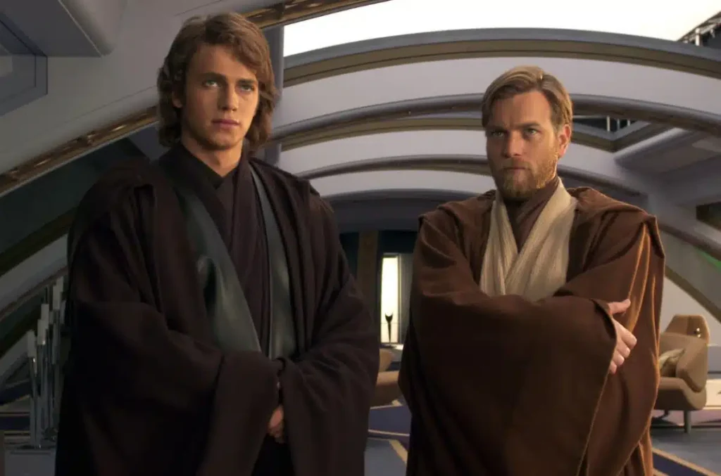 Deux hommes vêtus de robes brunes se tiennent côte à côte dans une salle futuriste de la Guerre des étoiles, le visage tourné vers l'avant avec des expressions neutres, laissant entrevoir une identité partagée et un possible exil.