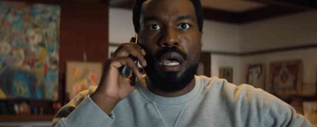 Un homme à l'expression surprise porte un téléphone à l'oreille alors qu'il se trouve à l'intérieur d'une pièce dont les murs sont ornés d'œuvres d'art, comme s'il réagissait à une nouvelle inattendue concernant la prochaine série Marvel de Wonder Man sur Disney+.