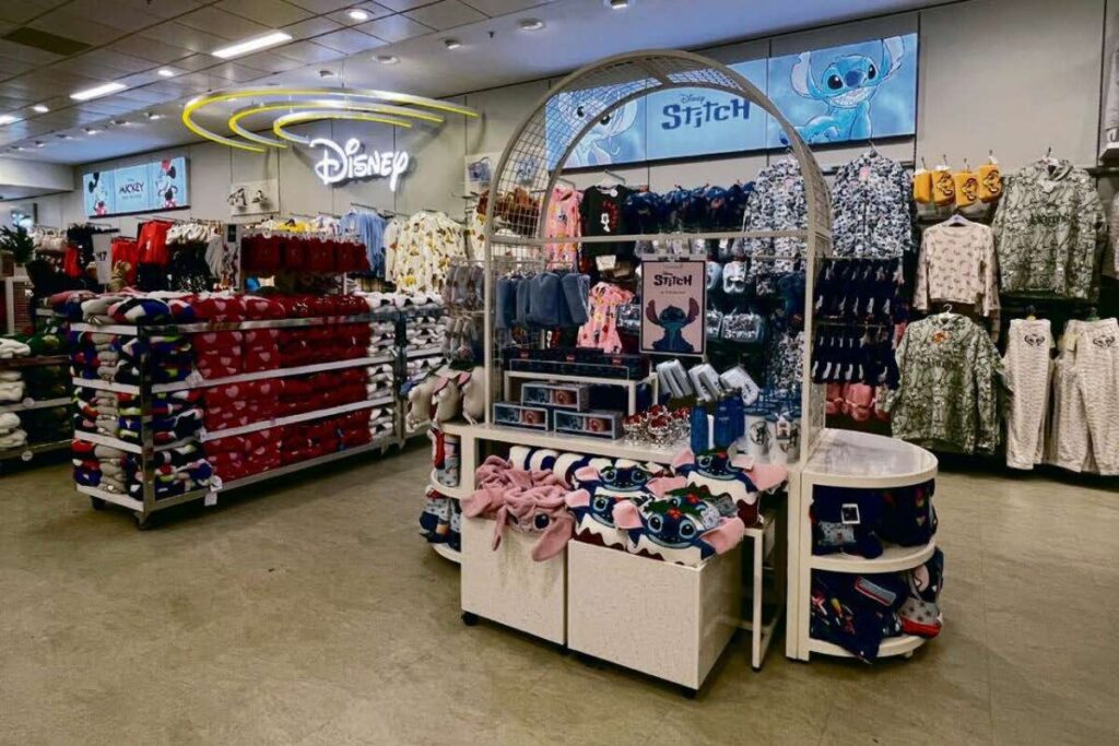 Magasin de vêtements Primark proposant des produits Disney et Stitch, avec des rayons de pyjamas, de sweats à capuche et d'accessoires à thème, le tout dans un style très abordable.
