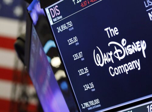 Un écran de la Bourse de New York montre le logo de Disney, des données boursières reflétant les résultats décevants et un drapeau américain en arrière-plan.