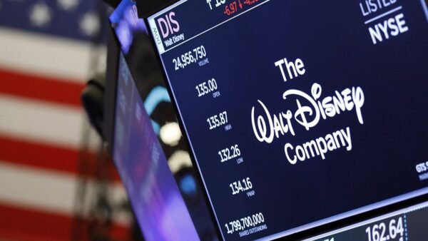 Un écran de la Bourse de New York montre le logo de Disney, des données boursières reflétant les résultats décevants et un drapeau américain en arrière-plan.