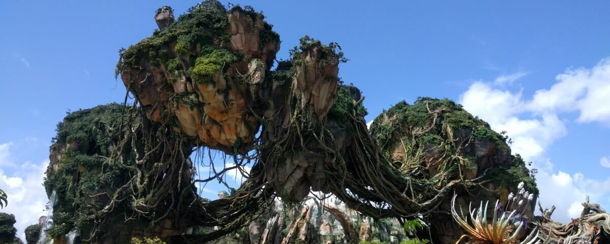 De grandes formations rocheuses flottantes recouvertes d'une végétation luxuriante sous un ciel bleu clair, évoquant la beauté d'un autre monde d'Avatar Land, la nouvelle attraction immersive de Disneyland Resort.
