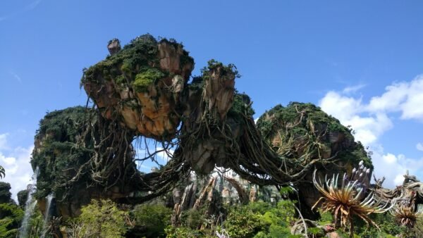 De grandes formations rocheuses flottantes recouvertes d'une végétation luxuriante sous un ciel bleu clair, évoquant la beauté d'un autre monde d'Avatar Land, la nouvelle attraction immersive de Disneyland Resort.