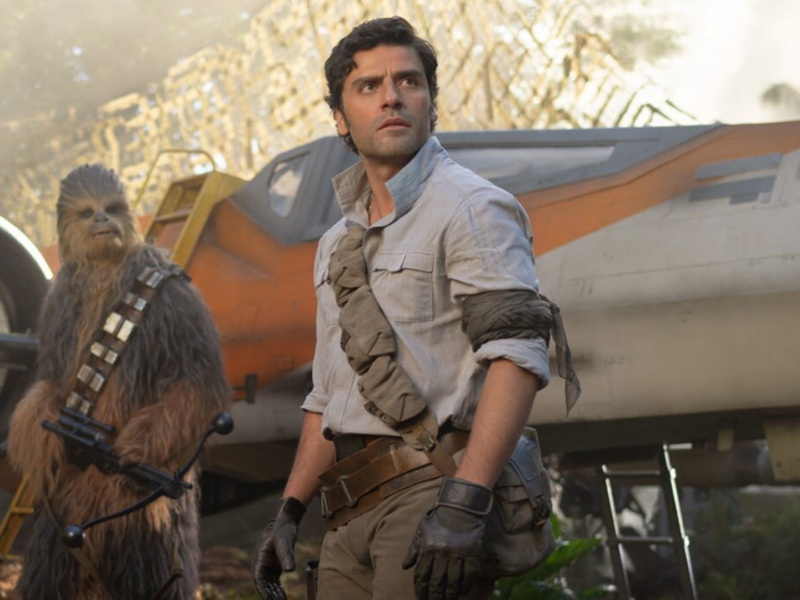 Un homme en tenue robuste se tient devant un vaisseau spatial de la Guerre des étoiles, à côté d'un grand personnage à fourrure tenant une arme, avec des arbres et de la brume en arrière-plan.