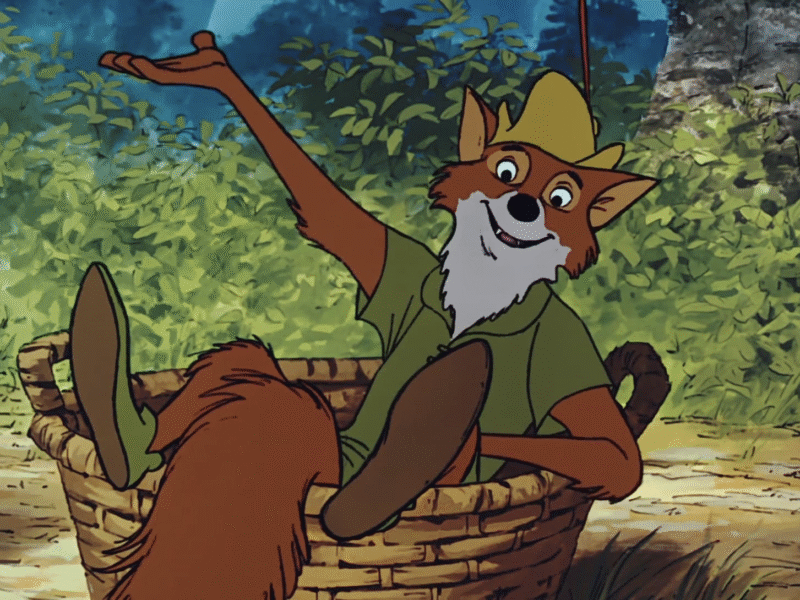 Le renard animé en chemise et chapeau verts, inspiré par Robin des Bois, est assis dans un panier tressé, un bras levé, entouré d'un feuillage luxuriant - une scène qui rappelle la première du film le 8 novembre 1973.